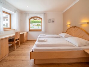 A bedroom with a bed, a desk, and a chair.