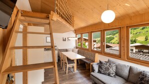 Un intérieur en bois avec une mezzanine, une table à manger et un canapé.