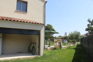 A residential building with a garage, a bicycle, and a patio area with chairs and a table.
