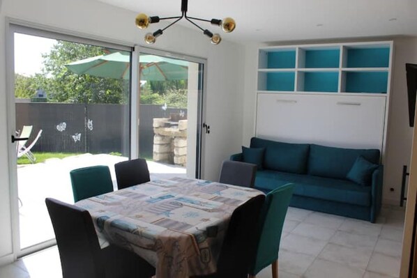 A dining area with a table and chairs, a blue sofa, and a sliding glass door leading to a patio.