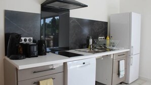 Een moderne keuken met een wit aanrecht, een zwarte afzuigkap, een witte koelkast en een vaatwasser.