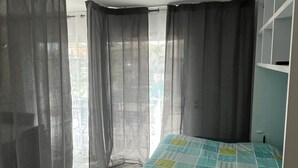 Een slaapkamer met een bed, gordijnen en uitzicht op de omgeving.