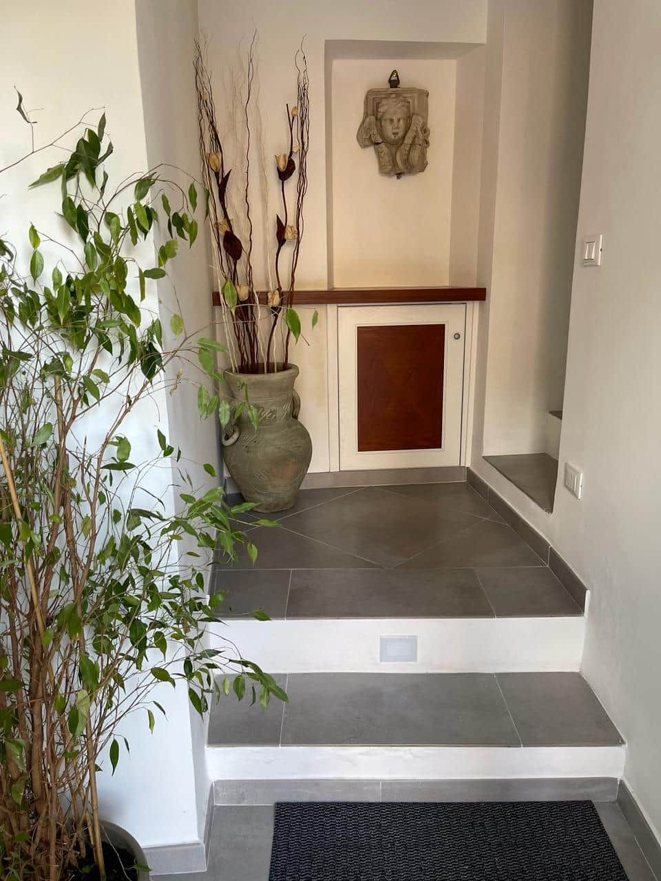 A staircase leading to a door with a decorative wall piece above it.