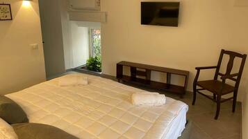 Ein Schlafzimmer mit einem Bett, einem Sessel, einem Fernseher und einem Fenster.