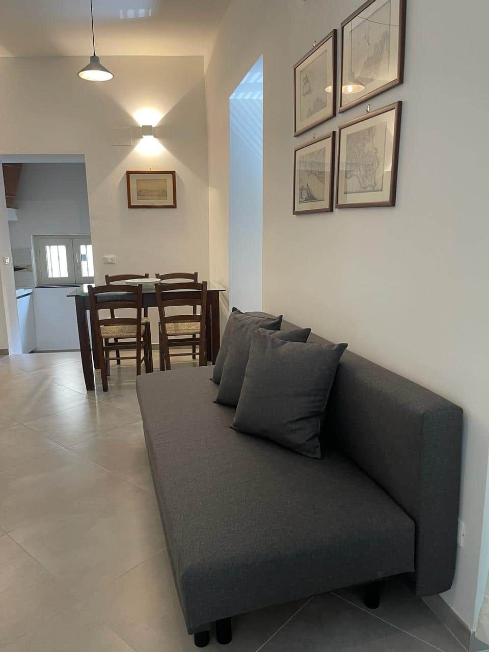 Un espace de vie comprenant un canapé, une table à manger, des chaises et des tableaux encadrés accrochés au mur.