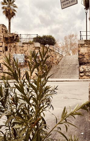 A stone staircase leading up to a building with a sign indicating directions to 'Pizza Indipendenza' and 'Palermo'. - Cathedral House Design (Palermo)