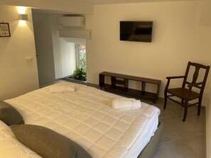 A bedroom with a bed, a TV, a chair, and a bench. - Cathedral House Design (Palermo)