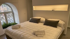 Una cama grande con un edredón blanco acolchado, dos almohadas y dos toallas dobladas.