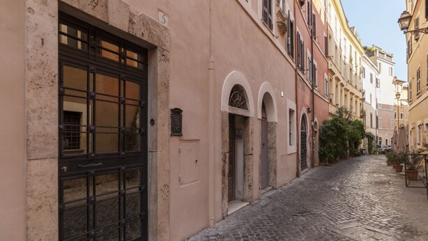 Una estrecha calle adoquinada flanqueada por edificios históricos, con una gran reja metálica y ventanas de arco.