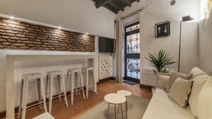 Un espacio habitable moderno con pared de piedra, muebles blancos, televisor de pantalla plana y planta en maceta.