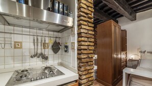 Una cocina con estufa a gas, utensilios colgantes y un pilar de ladrillo.