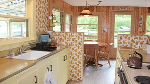 Una cocina con lavaplatos, estufa y comedor con sillas.