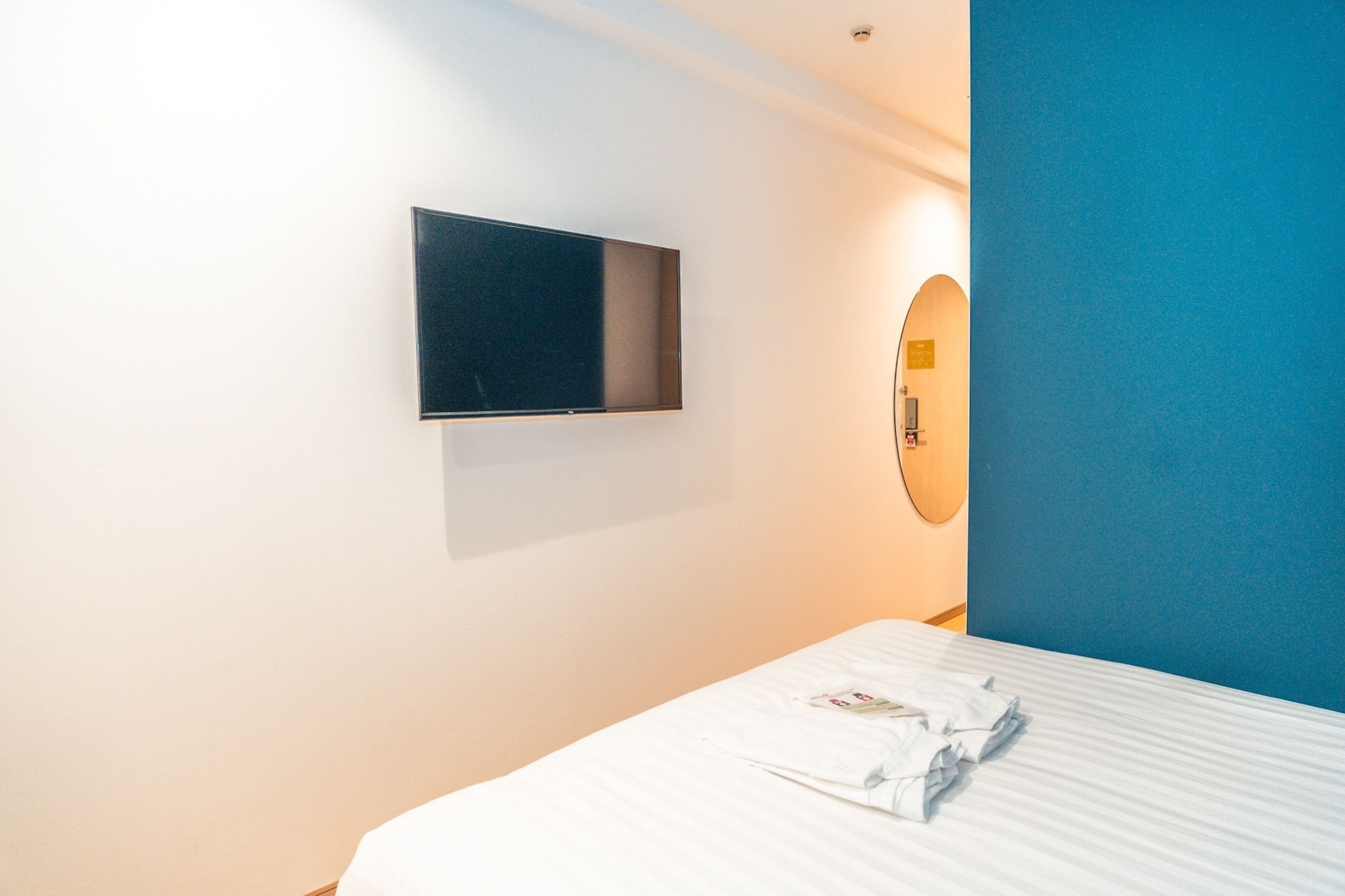 Habitació d'hotel amb un llit, un televisor de pantalla plana muntat a la paret i un mirall.