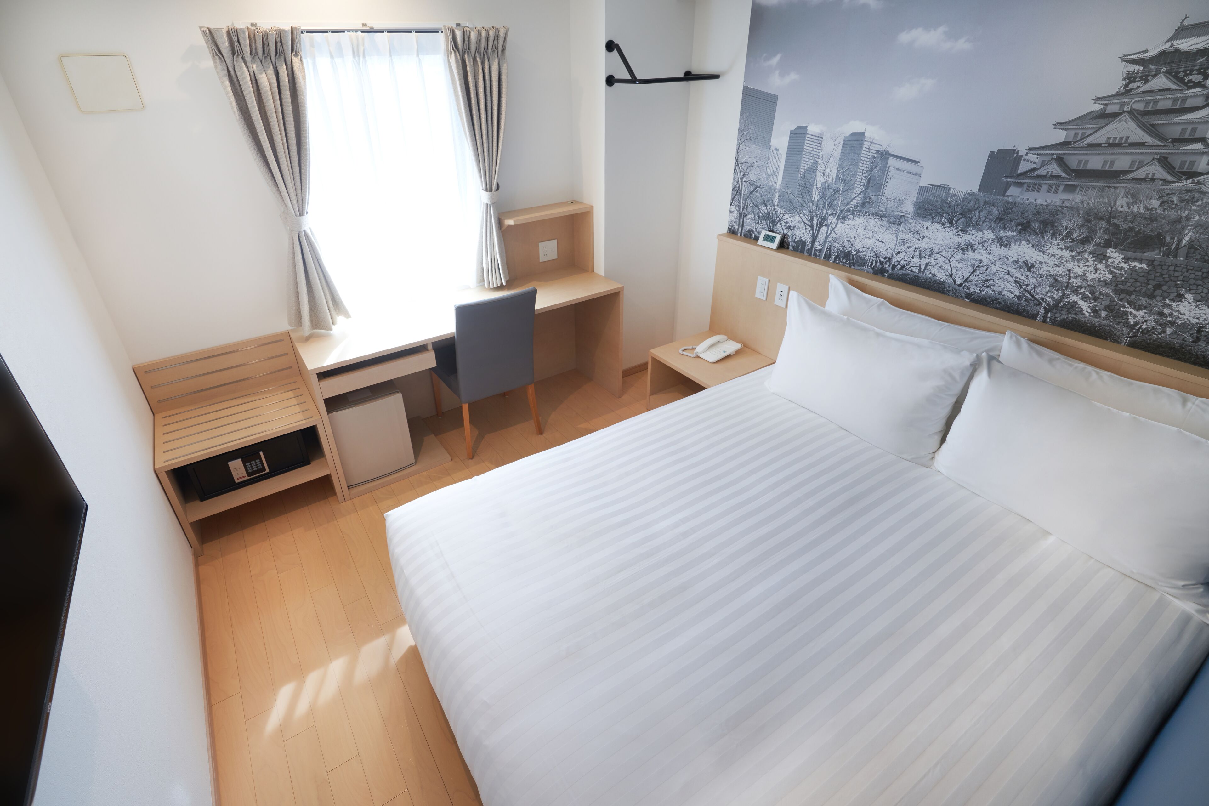 Ein Hotelzimmer mit Bett, Schreibtisch, Stuhl und Blick auf ein traditionelles Gebäude.
