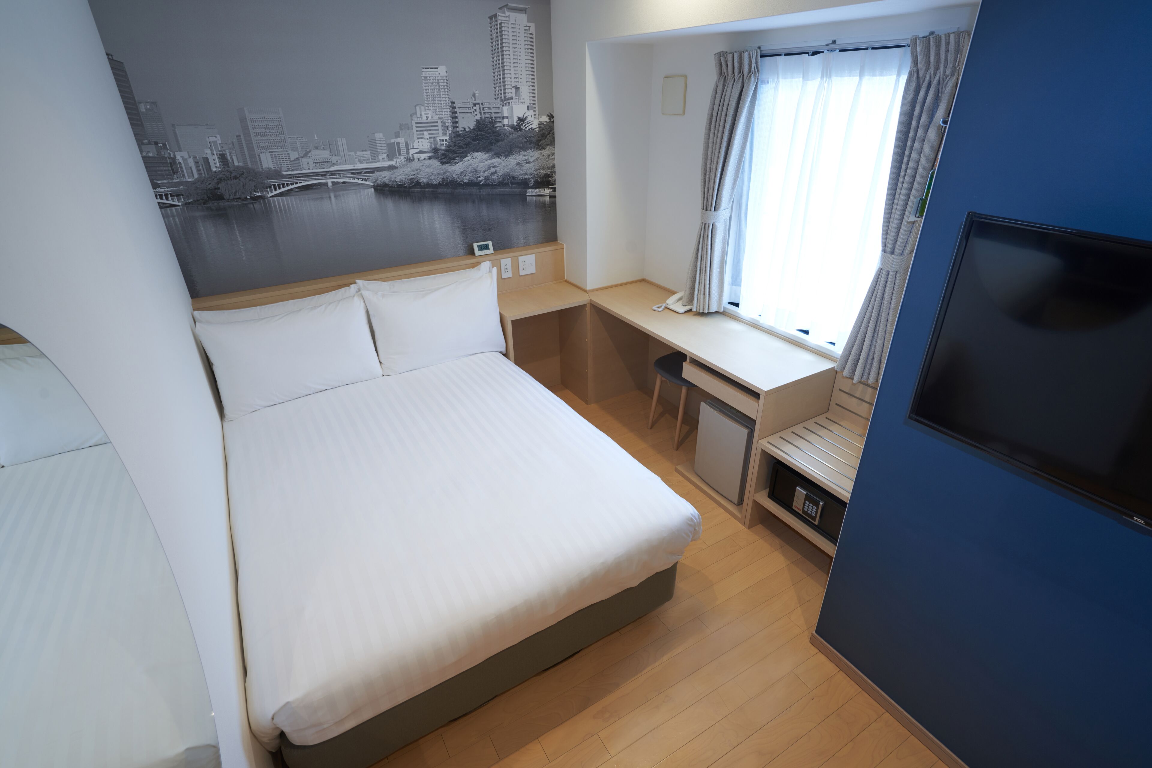 A hotel room with a bed, desk, and TV.