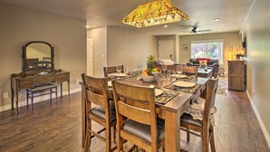 Un comedor con mesa de madera dispuesta para seis personas, una araña y un espejo en la pared.