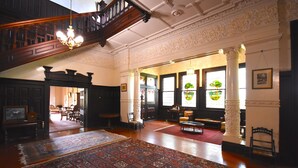 A spacious room with a large wooden staircase, a chandelier, and a large, ornate rug. - Kilmany Park Estate (Wurruk)