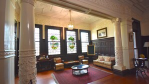 A spacious room with ornate columns, a large window with stained glass, a comfortable sofa set, and a coffee table. - Kilmany Park Estate (Wurruk)