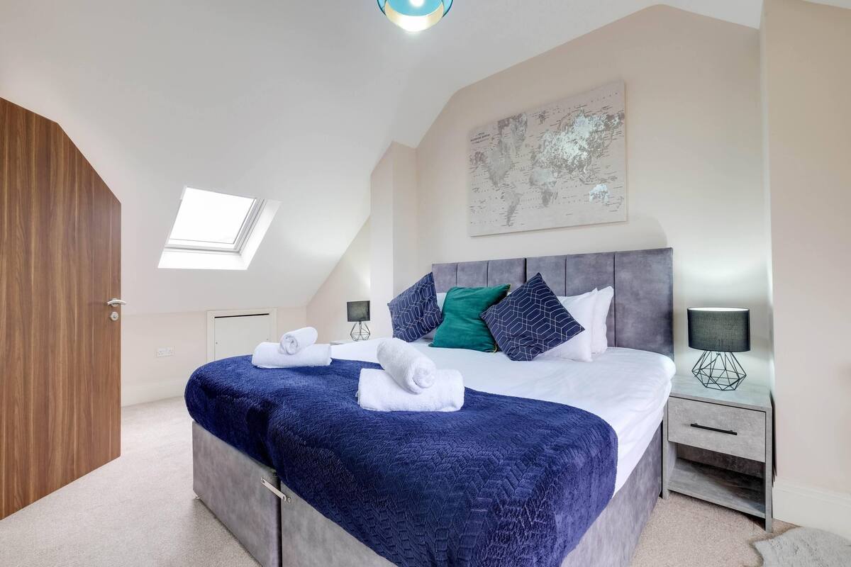 Een slaapkamer met een bed, een nachtkastje, een lamp, een kaart aan de muur en een dakvenster.