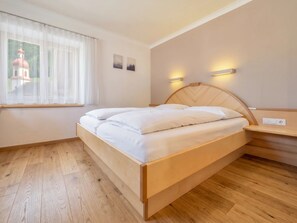 Ein Schlafzimmer mit einem hölzernen Bett, einem Fenster mit durchsichtigen Vorhängen und Wandleuchten.