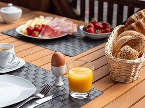 A breakfast table with plates of food, a basket of bread, a glass of orange juice, and a cup of coffee. - In the Center of Neustift - TWO Bedroom Apartment - sleeps 5 (Neustift im Stubaital)