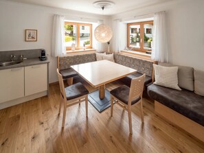 A compact kitchen with a dining area, wooden flooring, and a view through the windows. - In the Center of Neustift - TWO Bedroom Apartment - sleeps 5 (Neustift im Stubaital)