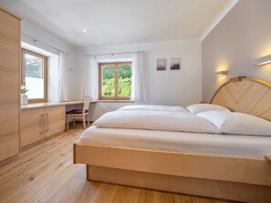 A bedroom with a bed, a desk, and a window with a view of greenery. - In the Center of Neustift - TWO Bedroom Apartment - sleeps 5 (Neustift im Stubaital)