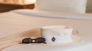 A bed with a white sheet, a straw hat, and a pair of sunglasses.