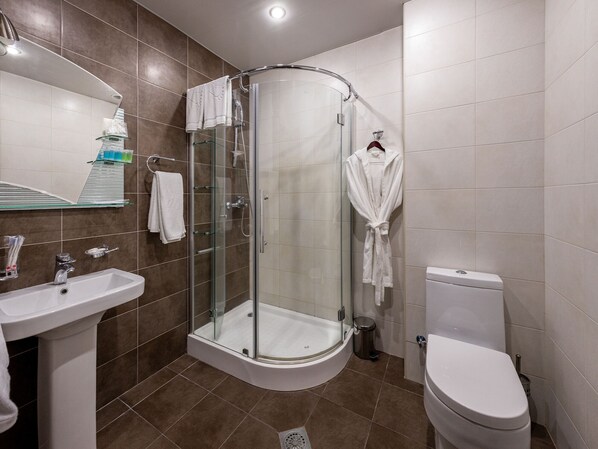Un baño moderno con ducha de vidrio, lavamanos blanco y retrete.