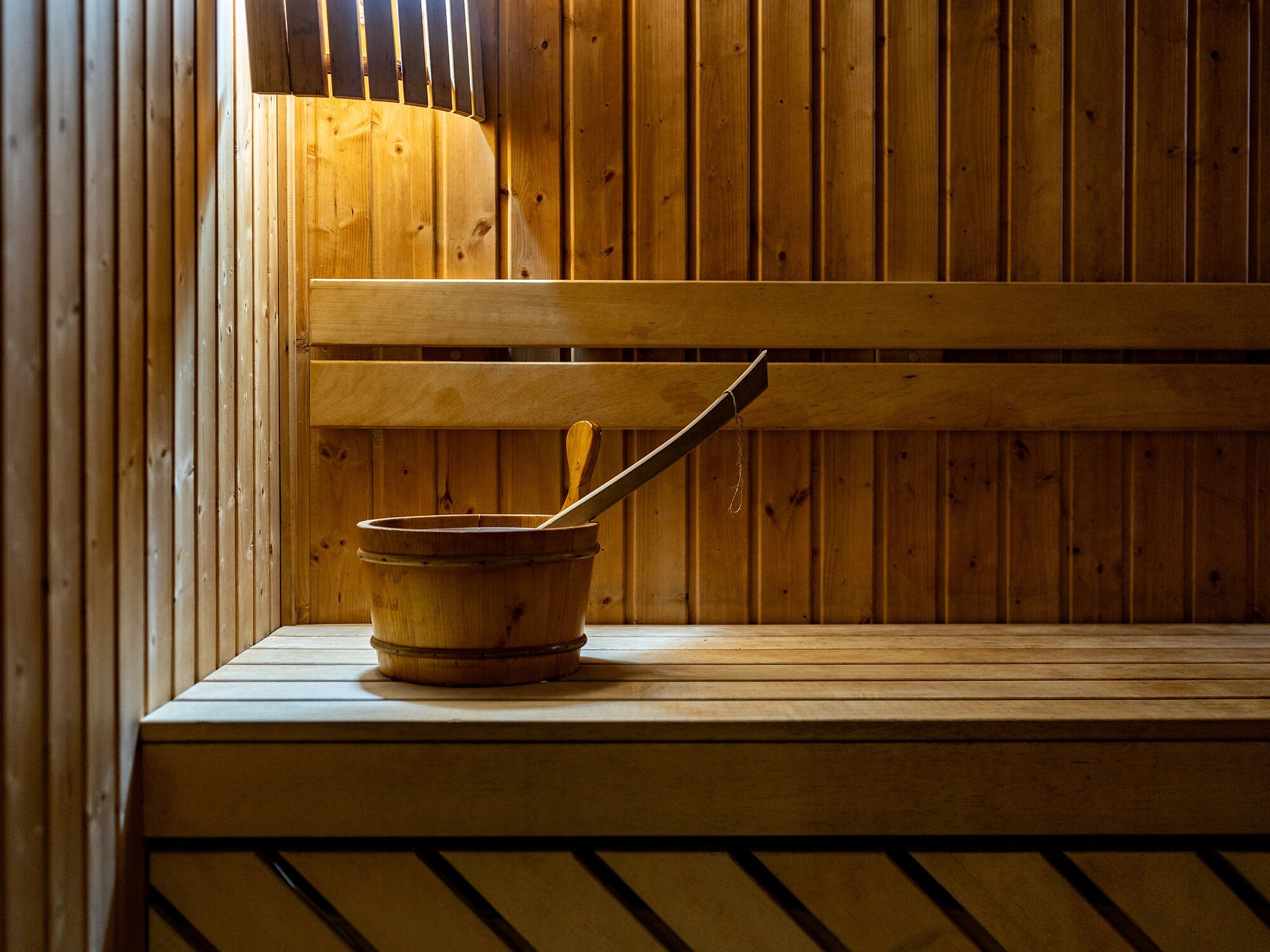 A wooden sauna bench with a wooden bucket and a ladle.