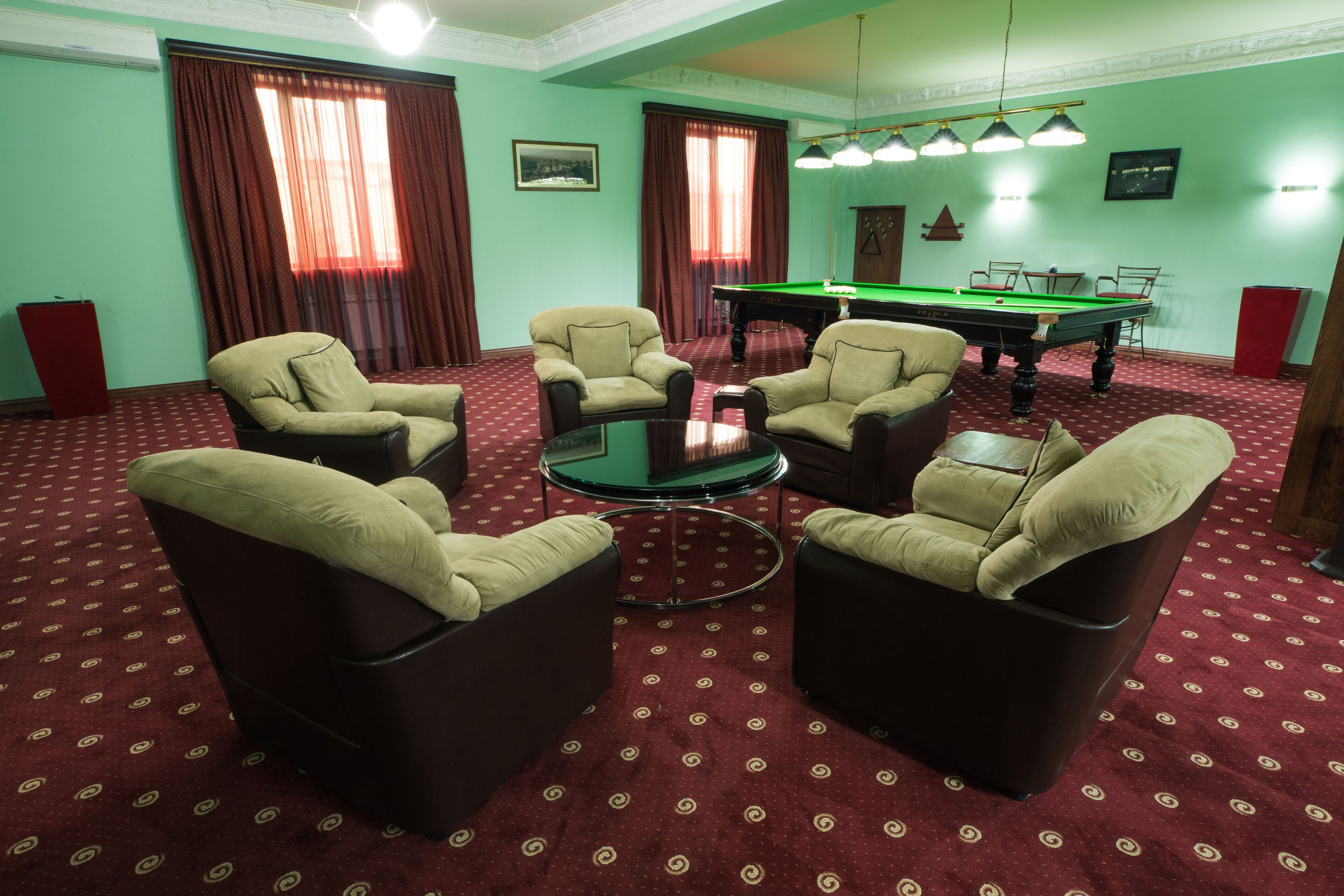 A room with four armchairs, a pool table, and a billiards table.