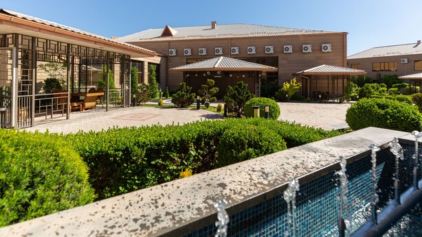 Een hotel met zwembad, terras en een verzorgde tuin.