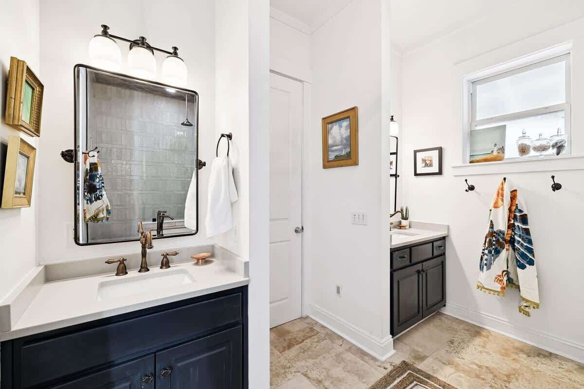 Ein Badezimmer mit einem großen Spiegel, einem Waschbecken, einem Handtuchhalter und einem Fenster.