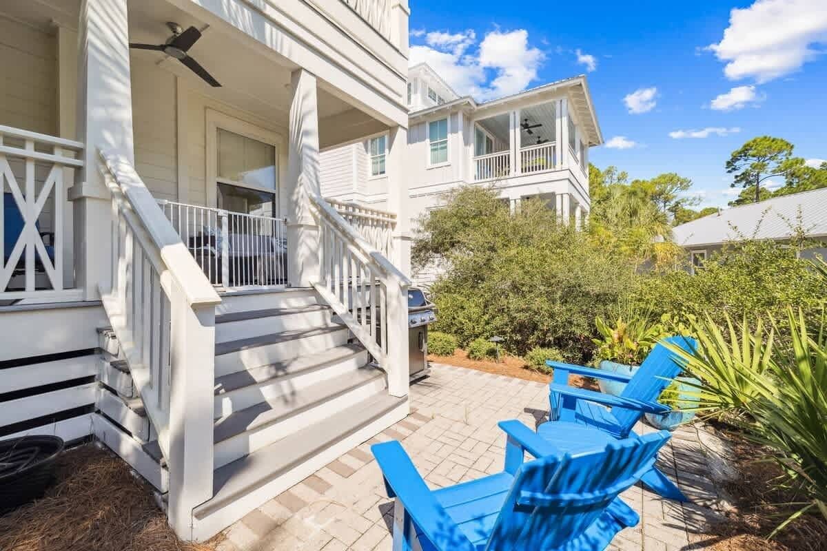 A white two-story house with a porch, outdoor seating, and a grill.