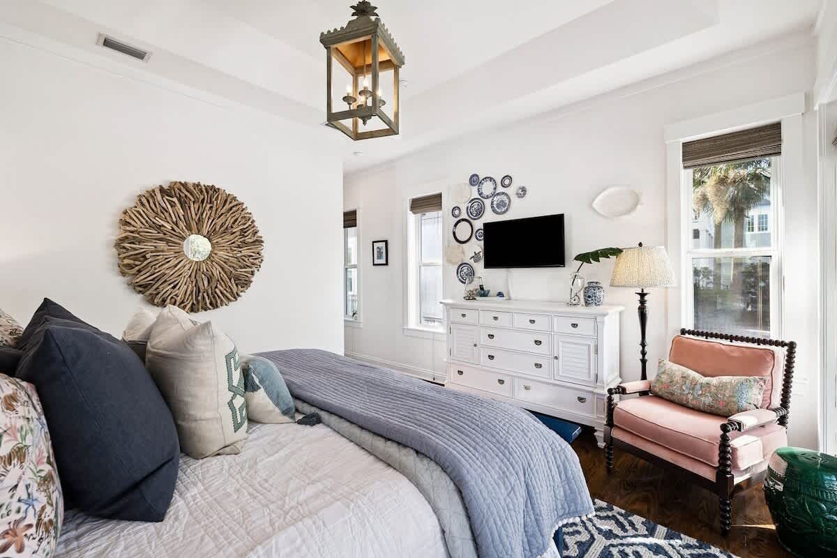A bedroom with a bed, dresser, chair, and wall decor.