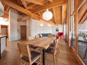 A spacious dining area with a wooden table and chairs, a red chair, and a hanging light fixture.