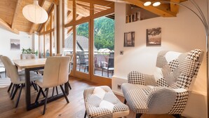 Ein modernes Interieur mit Holzbalken, einem Essbereich mit Tisch und Stühlen sowie einem Ohrensessel mit Hounds-Tooth-Muster.