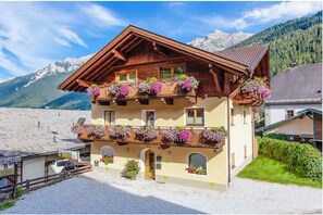 Ein traditionelles Chalet mit Holzbalkonen, einer Schotterauffahrt und einer Bergkulisse.