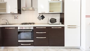 A modern kitchen with white and dark brown cabinetry, a built-in oven, a microwave, and a gas stove.
