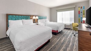 Ein Hotelzimmer mit zwei Betten, einem Schreibtisch, einem Stuhl und einem Fernseher.