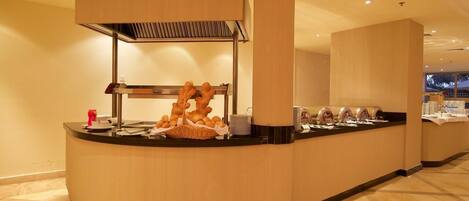 A buffet counter with a variety of food items and a coffee station.