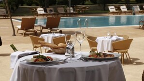 Una mesa de comedor preparada para dos personas, con platos de comida, copas de vino y cubiertos.