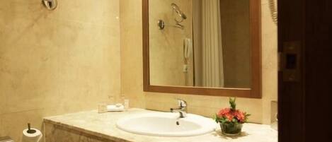 A bathroom with a marble sink, a large mirror, a towel rack, a trash can, and a scale.