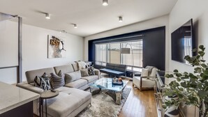 A modern living room with a sofa, coffee table, and a large TV. - Modern 4 Story Townhome -5 minutes walk to Deep Ellum & Fair Park! (Dallas)