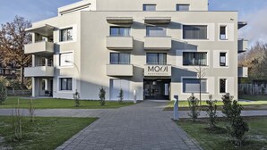 A modern multi-story apartment building with a flat facade, balconies, and a sign reading "MOOI Apartments". - MOOI Apartments Grenchen (Grenchen)