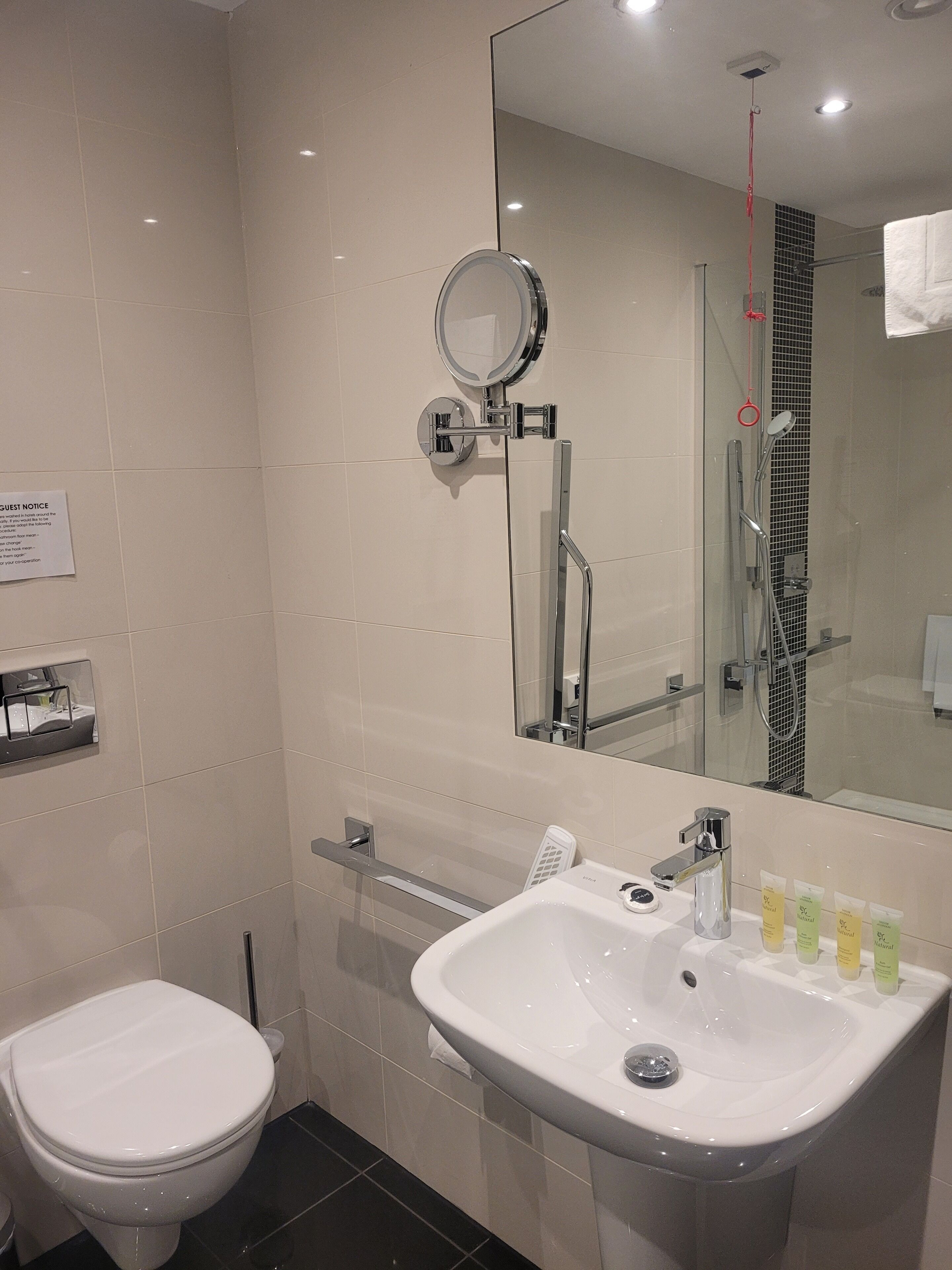 Een moderne badkamer met toilet, wastafel en spiegel.