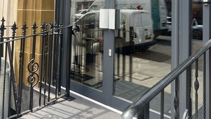 A building entrance with a glass door, a metal gate, and a sign indicating an automatic door. - Hatton Garden Hotel (London)
