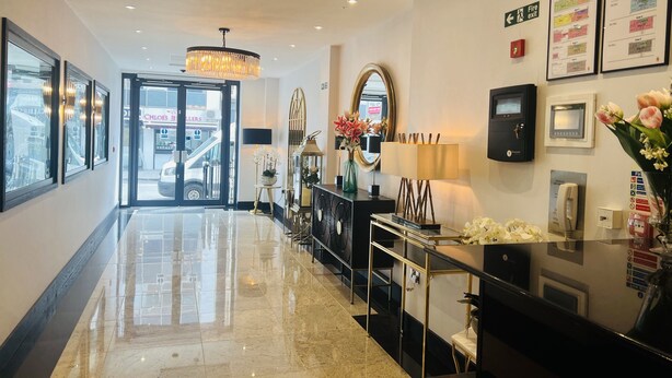 A hotel lobby with a polished marble floor, a chandelier, a reception desk, and a fire exit sign. - Hatton Garden Hotel (London)