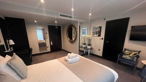 A hotel room with a large bed, a desk, a chair, a TV, and a mirror. - Hatton Garden Hotel (London)