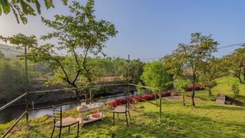 A serene outdoor seating area with a table and chairs, overlooking a river and lush greenery.